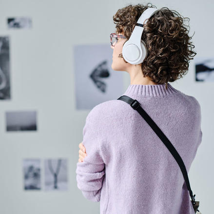 Museumsbesucherin betrachtet Ausstellung mit einem Audioguide